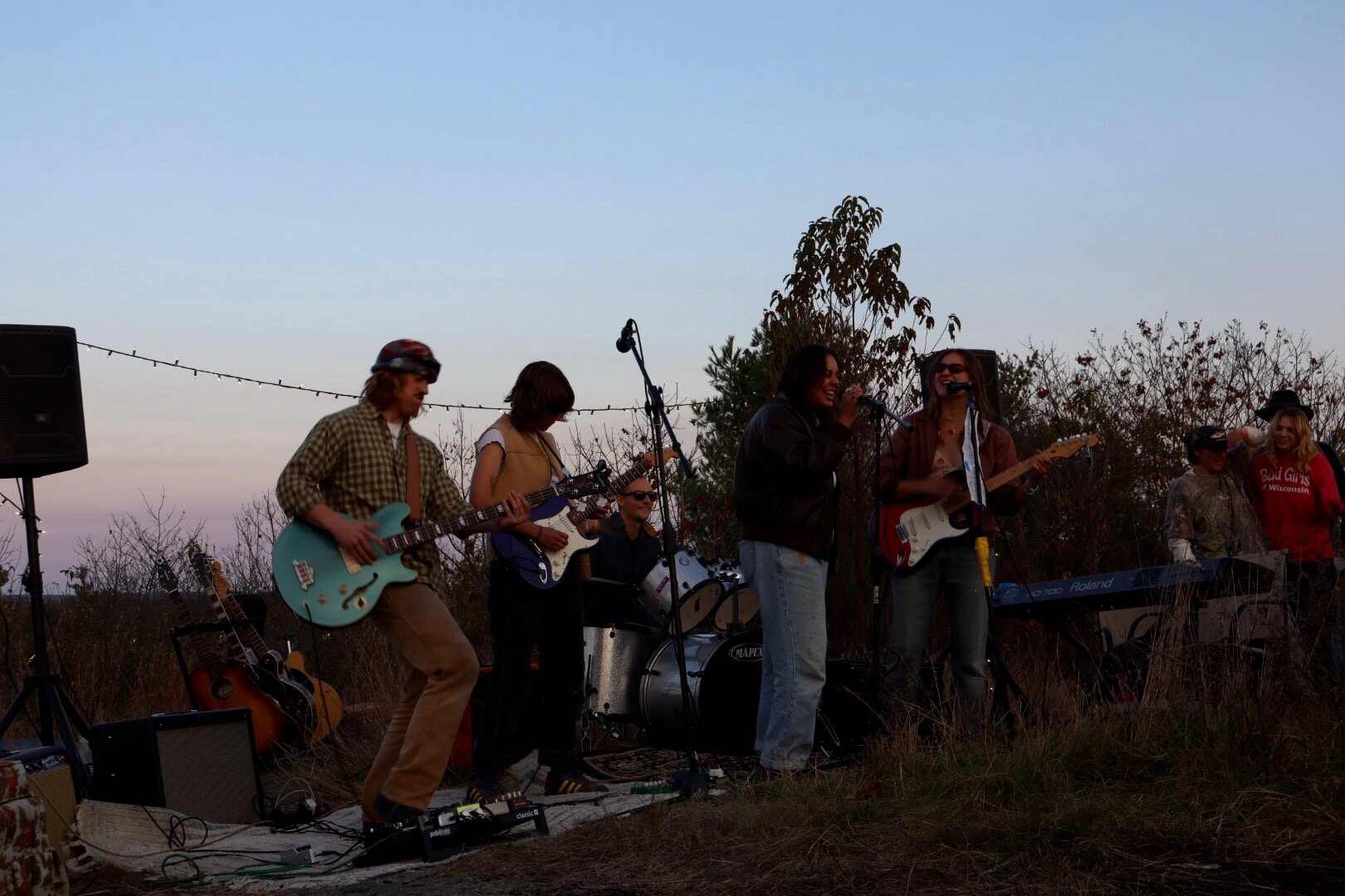 Audrey performing with a full band at sunset in a field