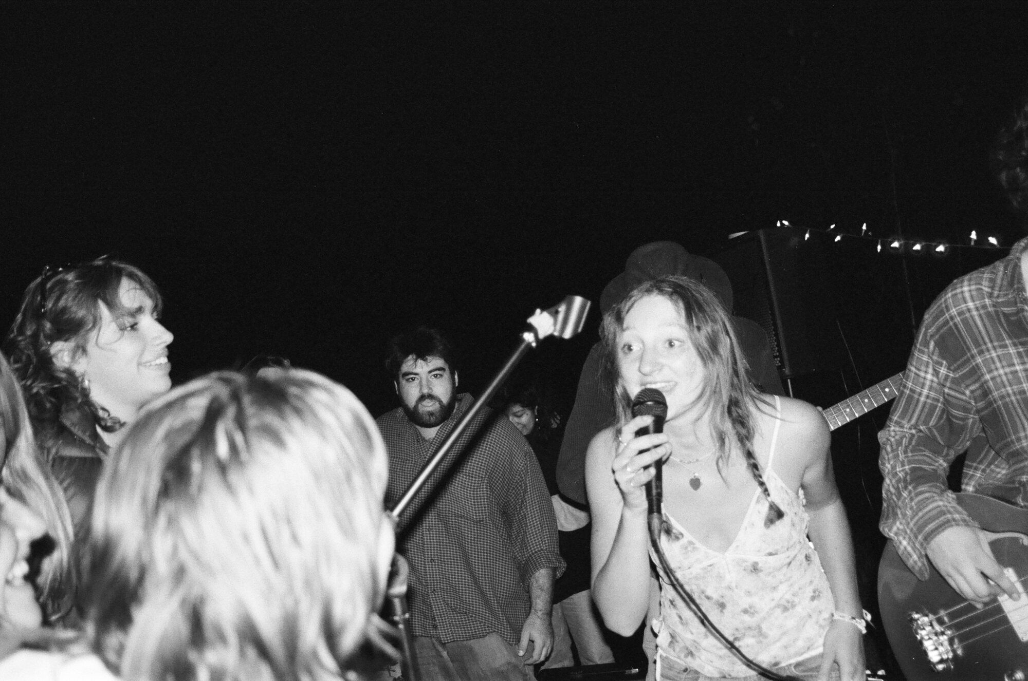 Black and white film photo of Audrey singing at a night show